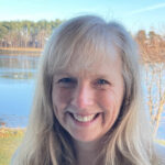 a long haired woman with bangs smiling for a headshot