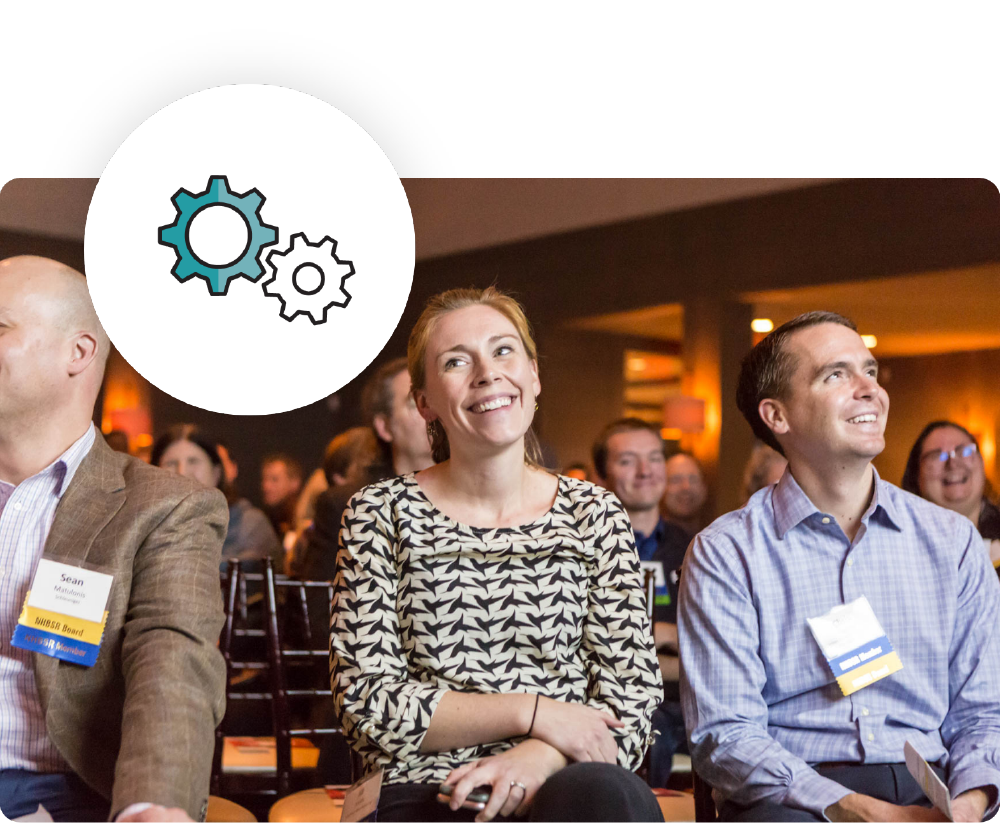 a woman and a man sitting at a conference smiling