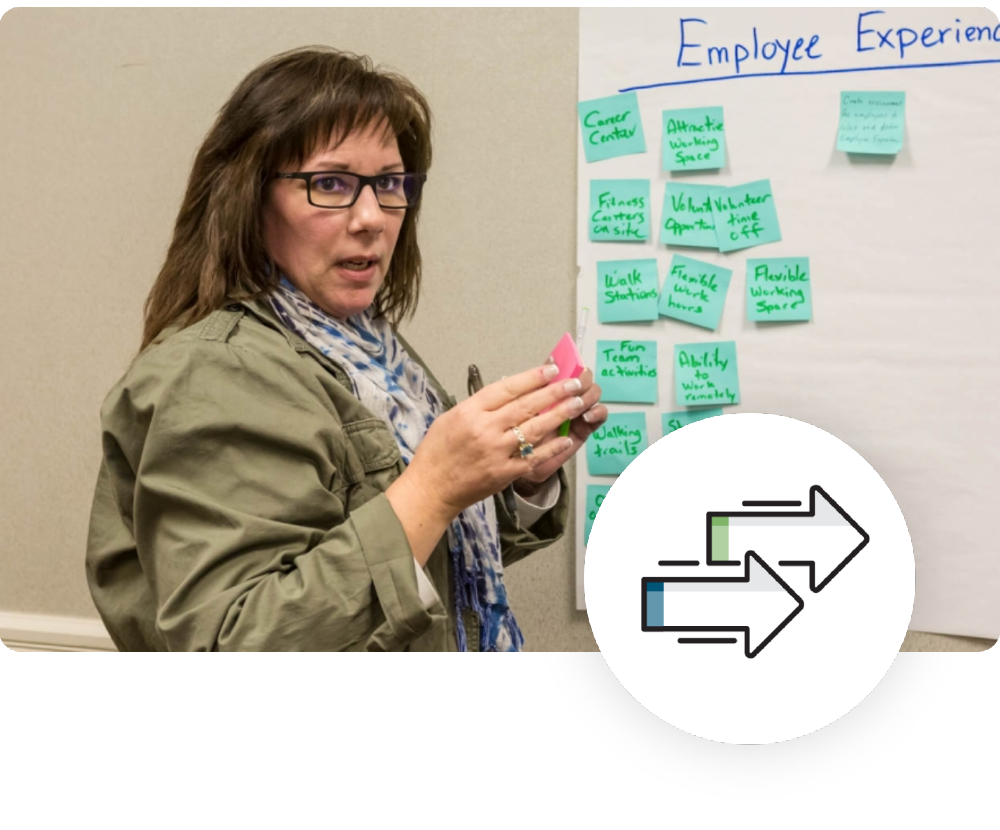 NHBSR Presentation a brown haired woman writing on post it notes and presenting it on a board